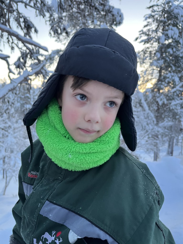 boy wearing hat with ear flaps and fleece snood from what to pack in Lapland list